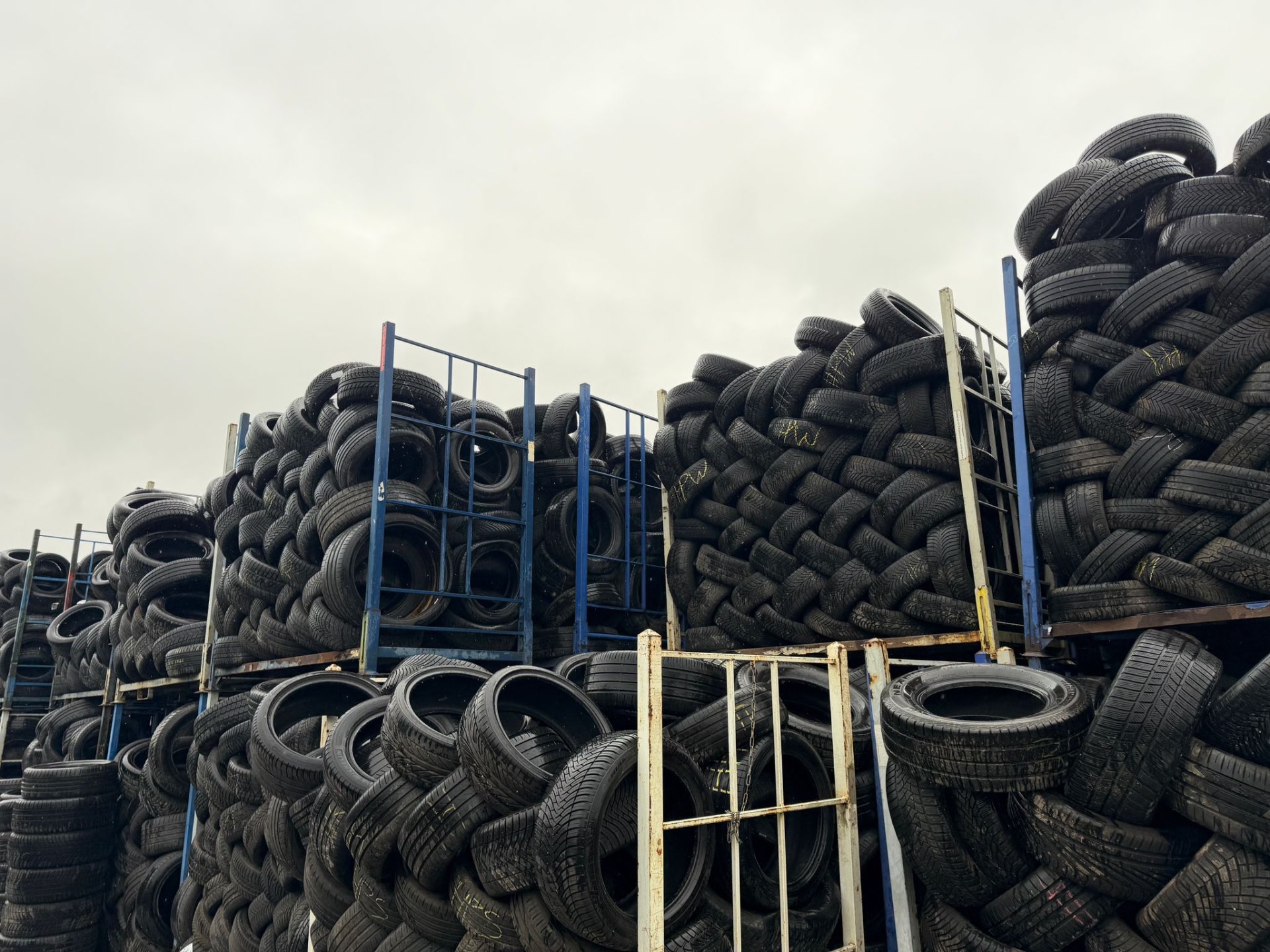 Used tyres stacked in woven layers on racks at the recycling yard