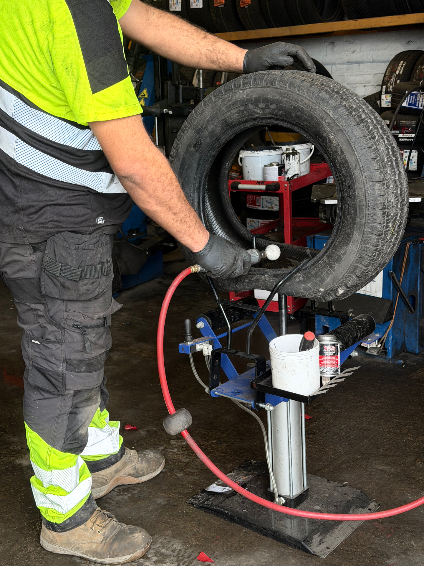 Fitter repairing a punctured tyre on a repair stand in the workshop